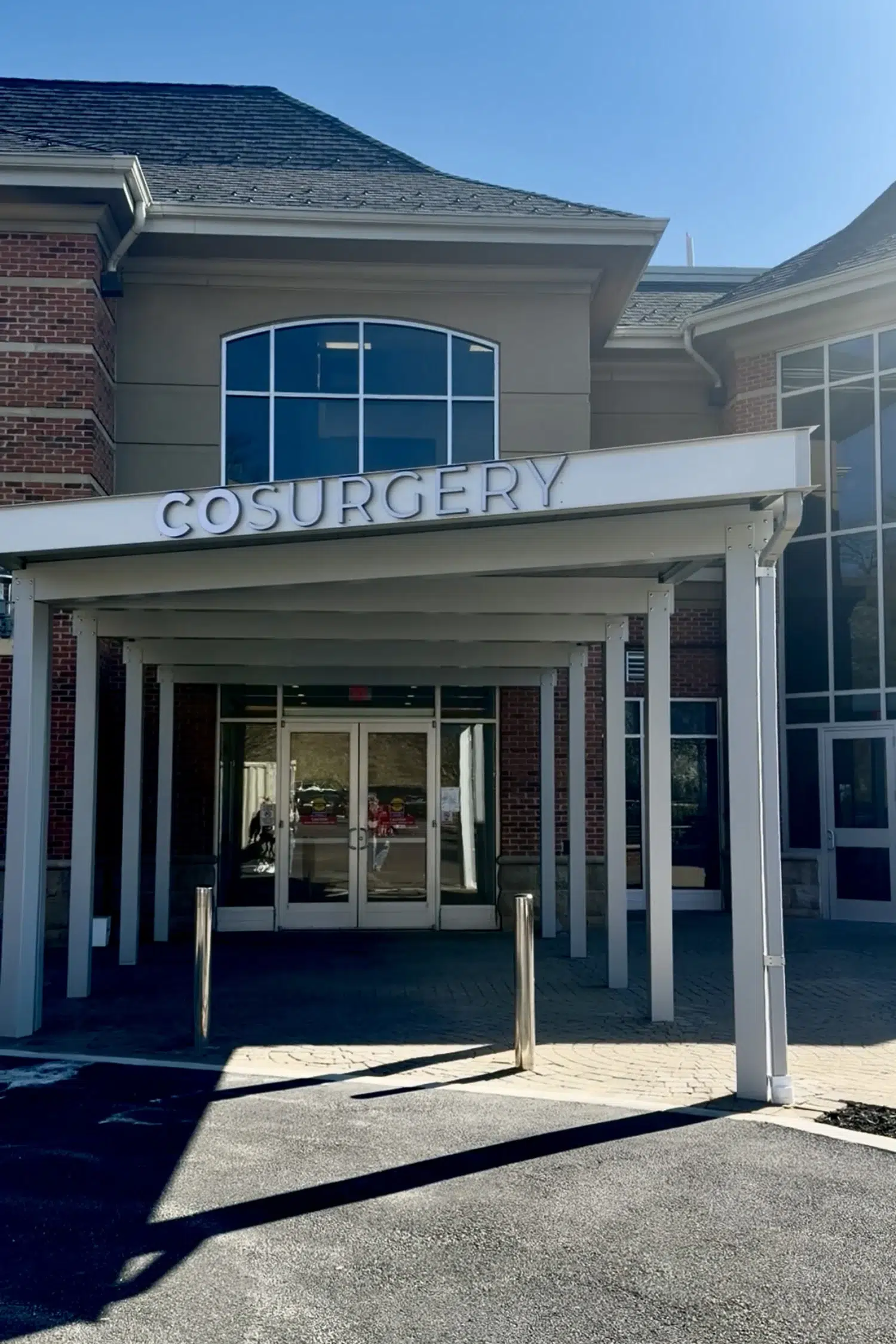 Covered entrance of COSURGERY medical facility with professional white canopy and glass doors.