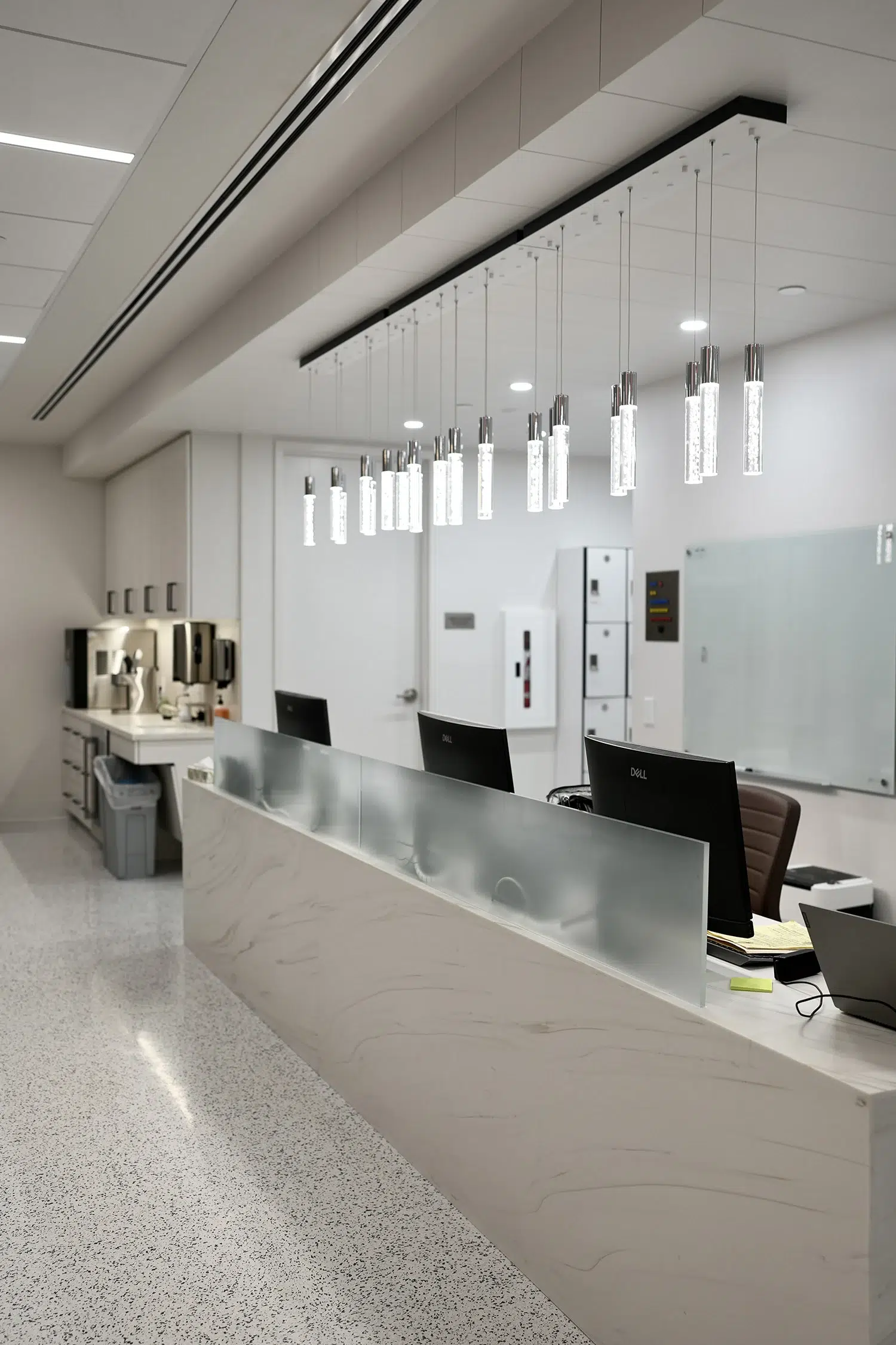 Luxury clinic nursing station with marble desk, crystal pendant lighting, and clean white cabinetry.