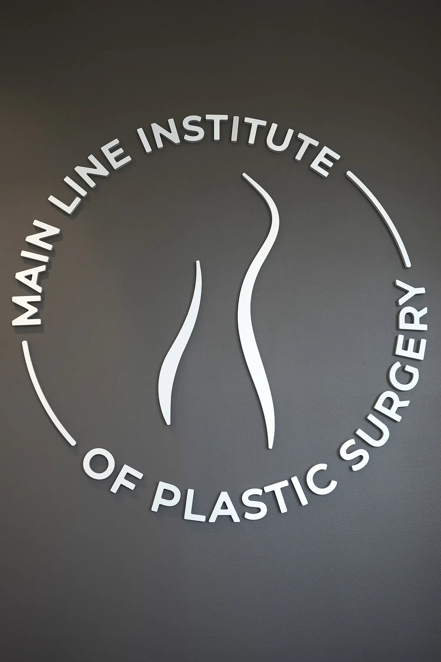Main Line Institute of Plastic Surgery wall logo featuring a minimalist body contour design.
