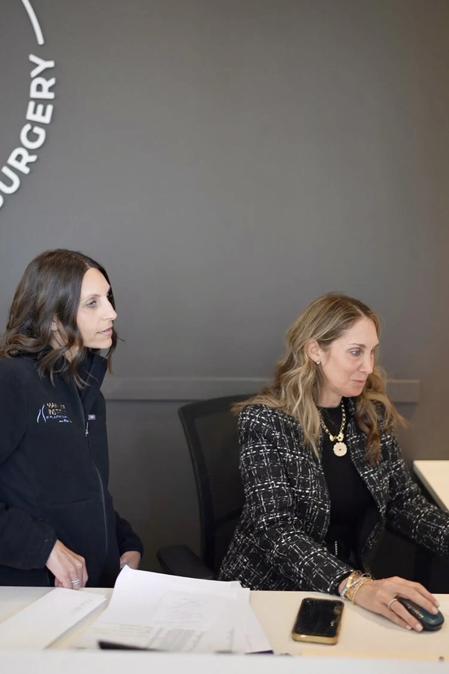 Plastic surgery clinic staff assisting a patient at the front desk reception area.