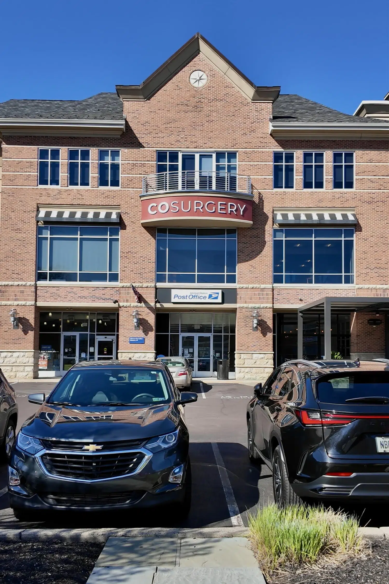 Professional brick exterior of COSURGERY medical center with large windows and blue sky.