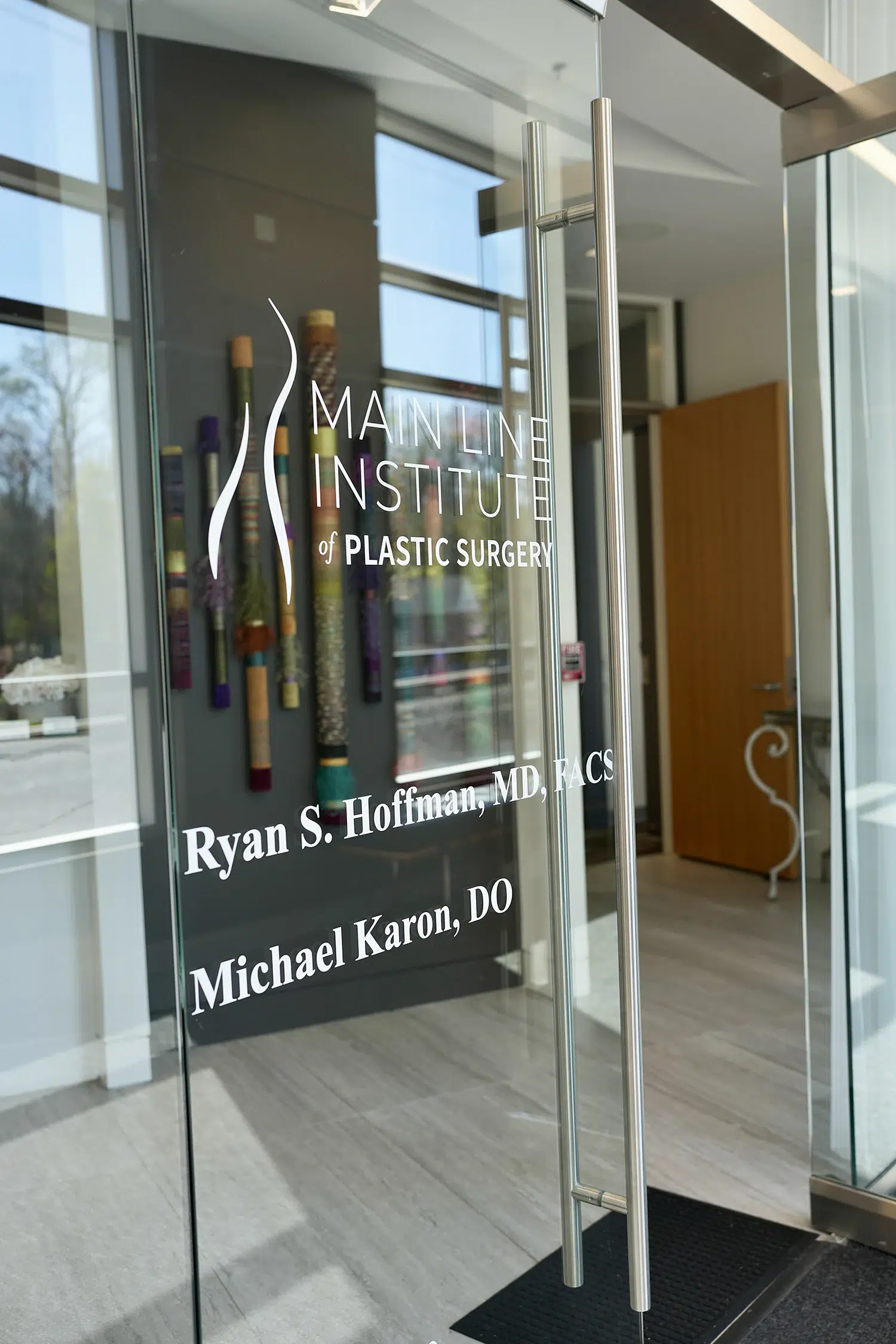 Glass entrance door of Main Line Institute of Plastic Surgery listing Dr. Ryan S. Hoffman and Dr. Michael Karon.
